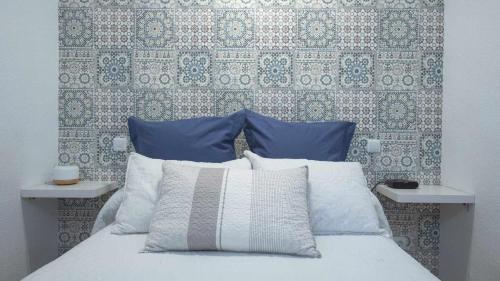 een bed met blauwe en witte kussens en een muur bij La Casa de San Miguel by Toledo AP in Toledo