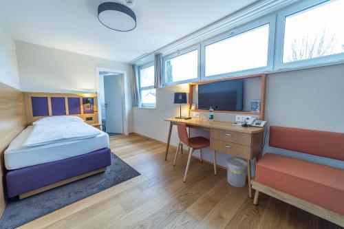 a bedroom with a bed and a desk with a computer at Dialoghotel Eckstein in Zug