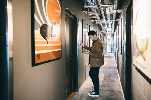 a man standing in a hallway looking at his cell phone at Rocca House by Larsen in Tallinn