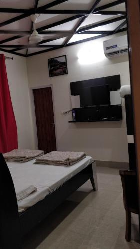 a bedroom with two beds and a flat screen tv at Kanva Farms in Kotdwāra