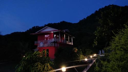 a red building at night with lights in front at Kanva Farms in Kotdwāra