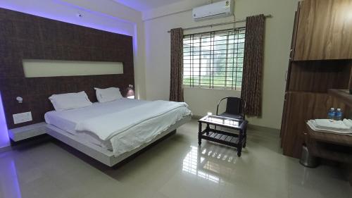 SringeriにあるSTAYMAKER Shubhodaya Lodgeのベッドルーム(白い大型ベッド1台、デスク付)