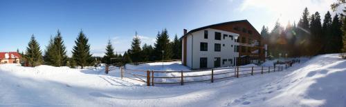 a building in the snow with a fence in front at Mountain-Rest Pension in Miercurea-Ciuc