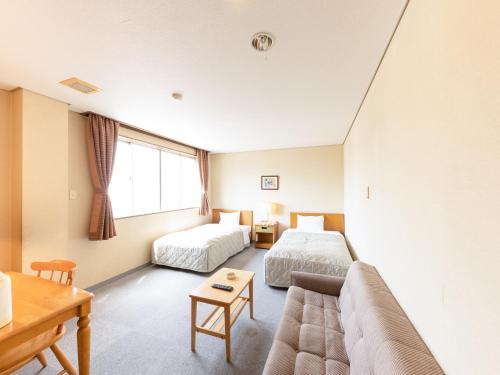a hotel room with two beds and a couch at Tabist Kanko Business Hotel Matsuyama Hida Takayama in Takayama