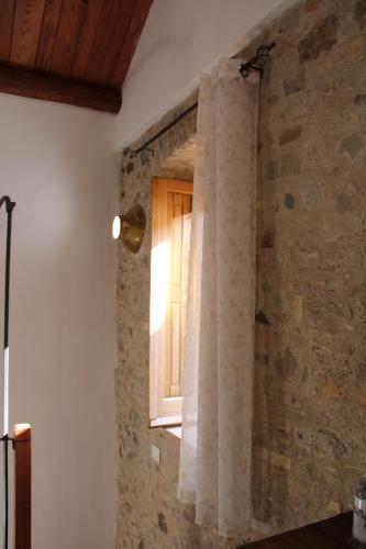 a room with a window and a stone wall at Ospitalità diffusa Jungi Mundu in Camini
