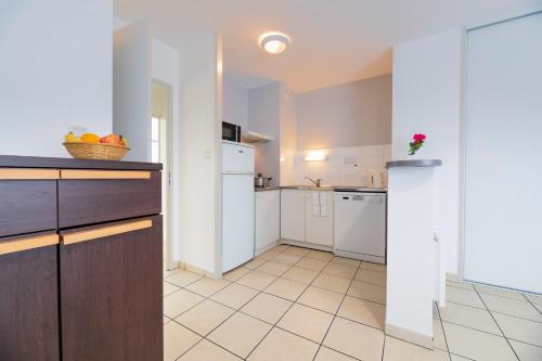 a kitchen with white appliances and a tile floor at Cerise Nantes Atlantis in Saint-Herblain
