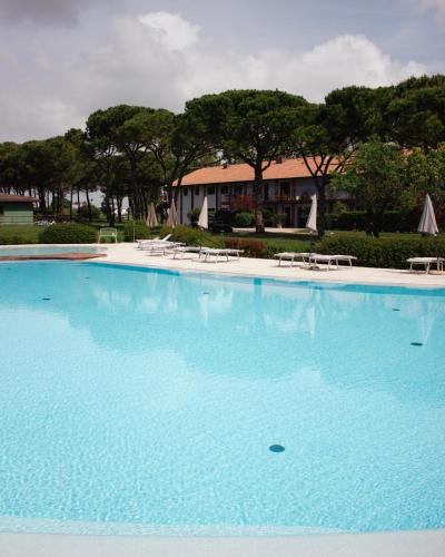 a large blue swimming pool with chairs and trees at Residenze Di La' Dal Fiume in Caorle