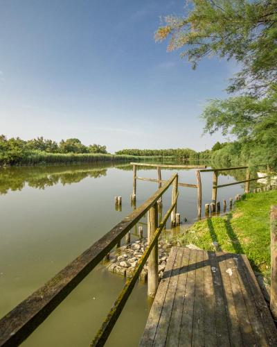 a wooden bridge over a river with trees in the background at Residenze Di La' Dal Fiume in Caorle