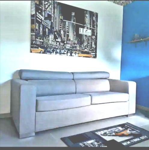 um sofá branco num quarto com uma fotografia na parede em Chambre privée dans maison em Le Tampon