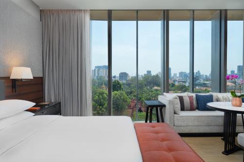 a bedroom with a bed and a couch and a large window at Hyatt Regency Phnom Penh in Phnom Penh