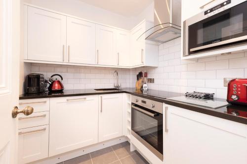 a white kitchen with white cabinets and appliances at JOIVY Cozy Apt near Edinburgh Castle in Edinburgh