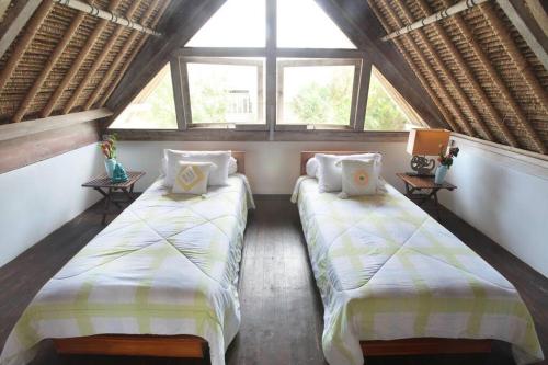two beds in a room with two windows at Villa Lumba Lumba - Oceanfront & Spectacular View! in Nusa Lembongan