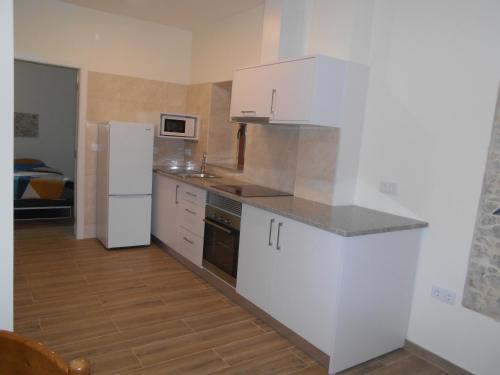 a kitchen with white cabinets and a white refrigerator at Casa do forno in Salir de Porto