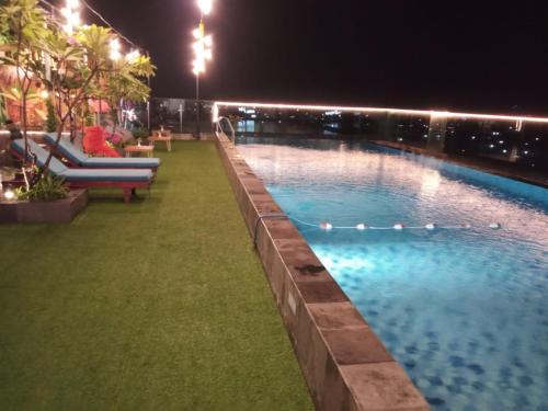 a swimming pool at night with a person sitting on a chair at Zigna Kampung Batik in Solo