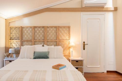 1 dormitorio con 1 cama blanca grande y cabecero de madera en Villa El Castañal con Piscina Privada, en Vigo