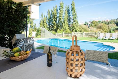 a table with a bottle of wine and a basket of fruit at Villa El Castañal con Piscina Privada in Vigo