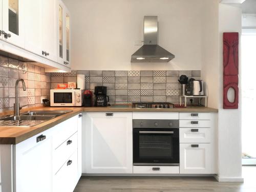 a kitchen with white cabinets and a sink at Naked House Sardinia in Bari Sardo