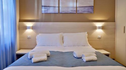 a bedroom with a large bed with two towels on it at Pianomare Riviera Apartments and Rooms in Imperia