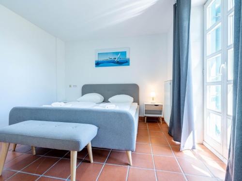 une chambre avec un lit, une chaise et une fenêtre dans l'établissement Feriendorf Rugana - Klassik Ferienwohnung mit 2 Schlafzimmern und 2 Terrassen D55, à Dranske
