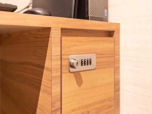 a wooden drawer with an alarm clock on it at Tabist Hotel Smart Sleeps Oita Station in Oita