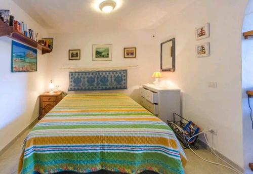 a bedroom with a bed with a colorful striped bedspread at Luminoso monolocale con vista mare in Porto San Paolo