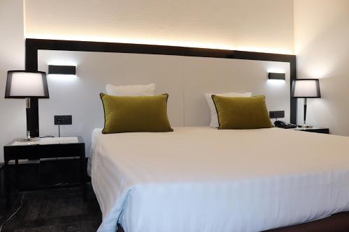 a bedroom with a large white bed with green pillows at Hotel Floris Arlequin Grand-Place in Brussels