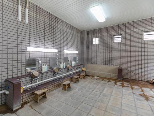 a bathroom with four urinals and benches in a room at Tabist Nisseiya Beppu Kannawa in Beppu
