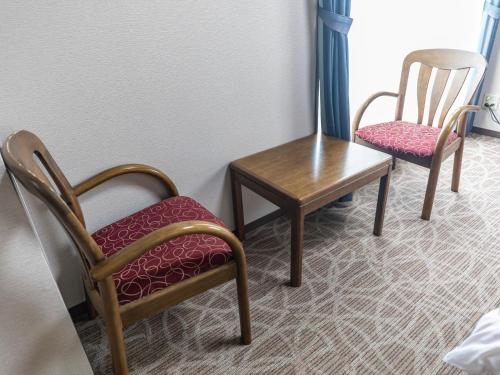 two chairs and a table in a room at Tabist Nisseiya Beppu Kannawa in Beppu