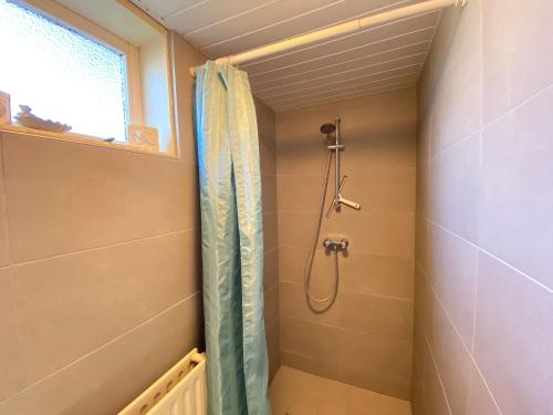 baño con ducha con cortina azul en Op 't Landtweg 37a, en Callantsoog