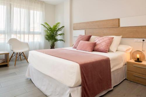 - une chambre avec un grand lit blanc et des oreillers roses dans l'établissement Viviendas con Fines Turísticos "Quivir Fleming", à Andújar