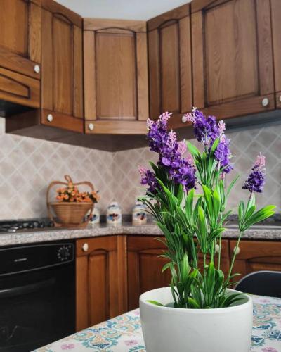 un jarrón con flores púrpuras sobre una mesa en una cocina en La Margherita - Casa vacanze, en Montallegro