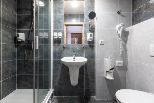 a bathroom with a shower and a sink and a toilet at OREA Hotel Arigone Olomouc in Olomouc
