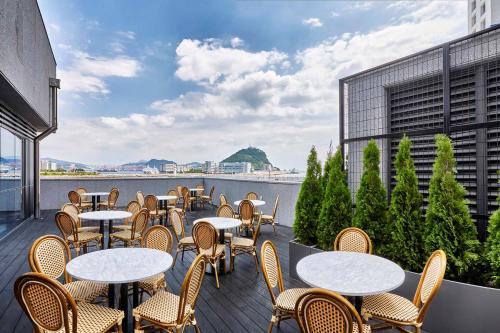 una fila de mesas y sillas en un balcón en Shiftdoor Residence Hari, en Busan