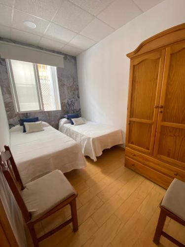 Pokój z 2 łóżkami i drewnianą szafką w obiekcie Amplio Piso en el Centro de Cádiz w Kadyksie