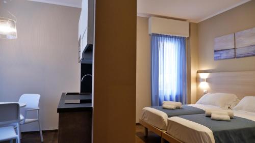 a bedroom with a bed and a desk and a window at Pianomare Riviera Apartments and Rooms in Imperia