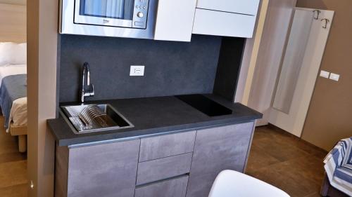 a small kitchen with a sink and a microwave at Pianomare Riviera Apartments and Rooms in Imperia