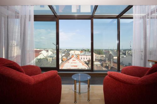 sala de estar con 2 sillas y ventana grande en OREA Hotel Arigone Olomouc, en Olomouc