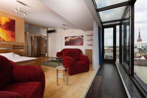 a living room with two red chairs and a large window at OREA Hotel Arigone Olomouc in Olomouc