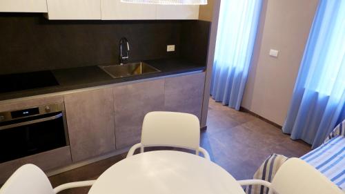 a kitchen with white chairs and a sink at Pianomare Riviera Apartments and Rooms in Imperia