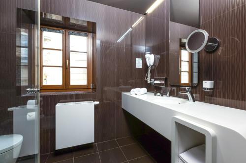 a bathroom with a sink and a toilet and a mirror at OREA Hotel Arigone Olomouc in Olomouc