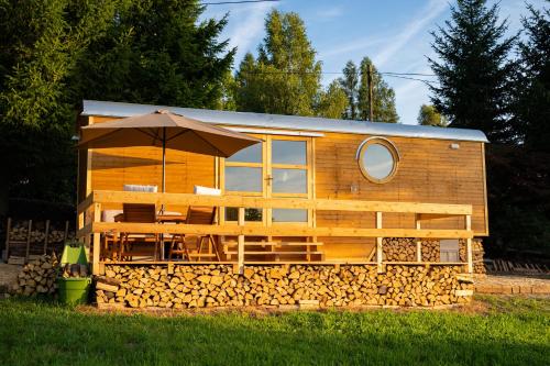 a house constructed out of logs with an umbrella at Maringotky Na Růžku in Nová Ves