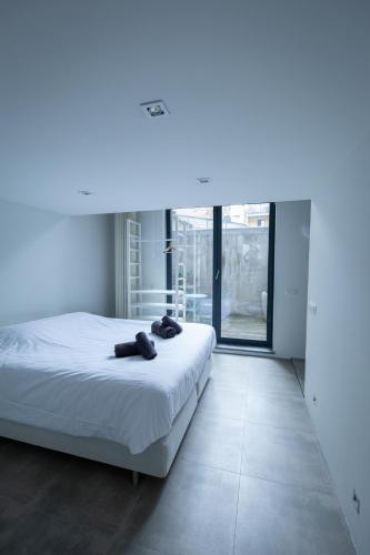 a white bedroom with a bed with two towels on it at Klapdorp in Antwerp