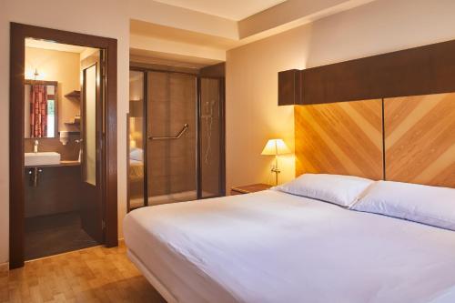 a bedroom with a large white bed and a shower at Silken Ordesa in Torla