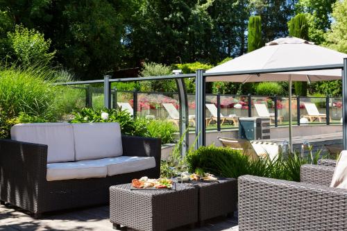 a patio with chairs and tables and an umbrella at Résidence la Réserve Genève Ferney Voltaire in Ferney-Voltaire