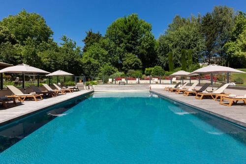 a swimming pool with lounge chairs and umbrellas at Résidence la Réserve Genève Ferney Voltaire in Ferney-Voltaire