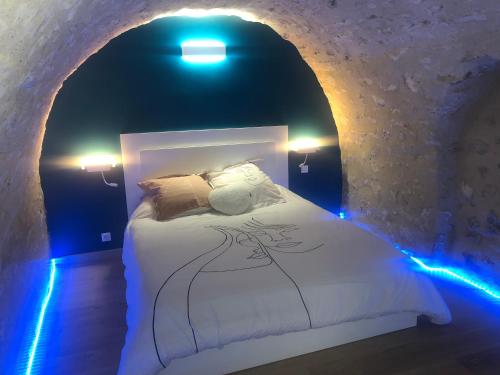 ein Schlafzimmer mit einem Bett in einer Höhle mit blauen Lichtern in der Unterkunft Trog'Love: Balnéo détente dans une troglodyte in Tours