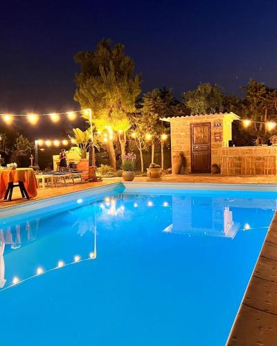 a swimming pool lit up at night with lights at B&B DOÑA FLOR in Parabita