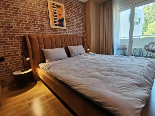 Cama grande en habitación con pared de ladrillo en Cozy One-Bedroom Apartment at Ljubovic Park, en Podgorica