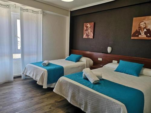 a room with three beds with blue pillows at Hostería VISTAPARK in El Astillero
