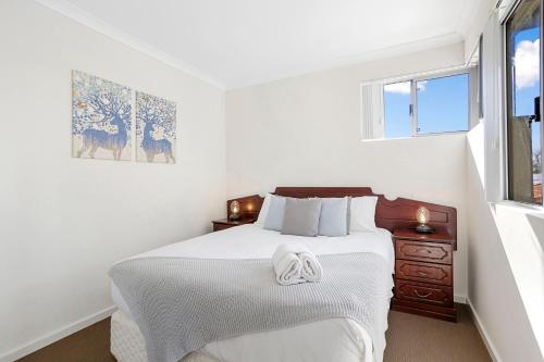 a white bedroom with a bed and two windows at 134 North Perth Nest For 4 Parking in Perth